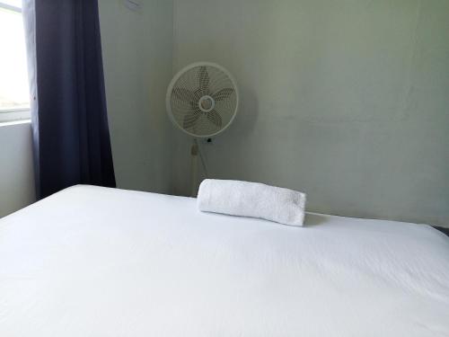 a white bed with a pillow and a fan at Christina's Guest House OFFICIAL in Little Corn Island