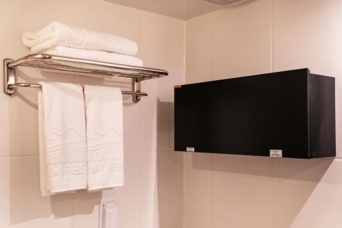 a bathroom with a tv and white towels at Hallim Resort in Jeju