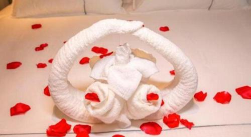 a bed with a white towel and red roses at Magnotel Hotel Dongxing Guomen Port in Fangcheng