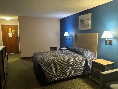 a hotel room with a bed and blue walls at Capital O Marysville Surf Motel Kansas in Marysville