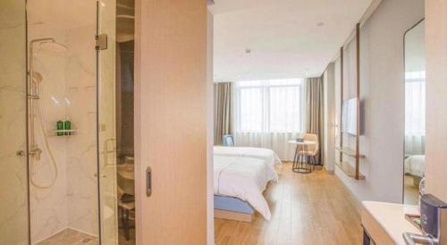 a bedroom with a bed and a glass shower at Magnotel Hotel Dongxing Guomen Port in Fangcheng