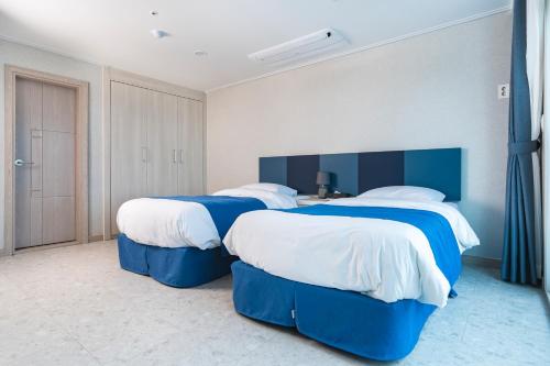 two beds in a room with blue and white at Hallim Resort in Jeju