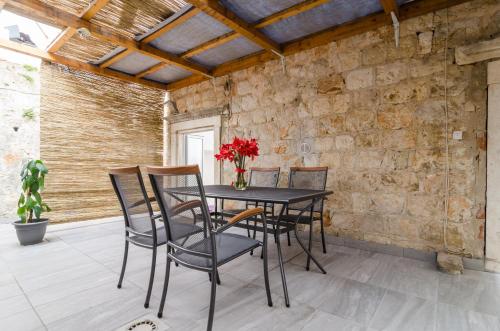 uma mesa e cadeiras num pátio com uma parede de pedra em La Porta Heritage em Dubrovnik