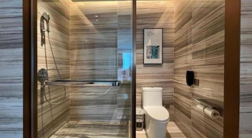a bathroom with a toilet and a glass door at Zhuhai Hongsanyi Hotel in Zhuhai