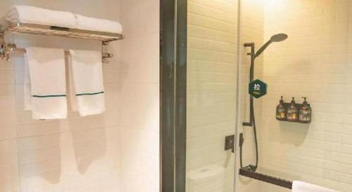 a bathroom with a shower with towels and a sink at City Comfort Premier Hotel Xiaogan Anlu Railway Station Dongda Times Square in Xiaogan
