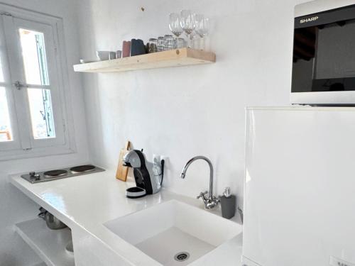 a white kitchen with a sink and a refrigerator at Andros memories in Batsi