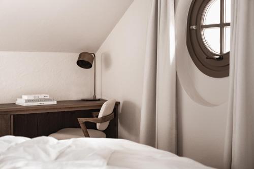 a bedroom with a bed and a desk and a window at stieg'nhaus Design Boutique Hotel in Mühlbach am Hochkönig