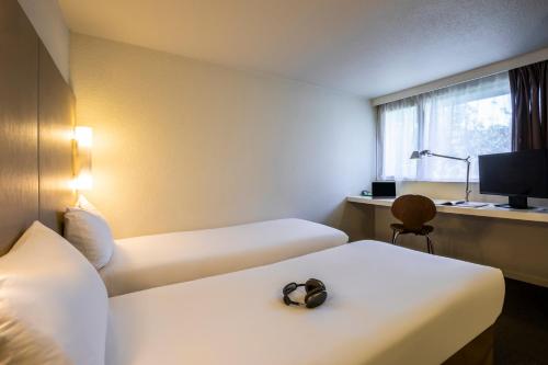 a hotel room with two beds and a window at Campanile Pontarlier in Pontarlier