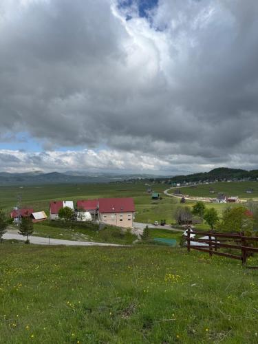 Blick auf einen Bauernhof mit einem Zaun und einem Feld in der Unterkunft Hideaway with a view in Žabljak