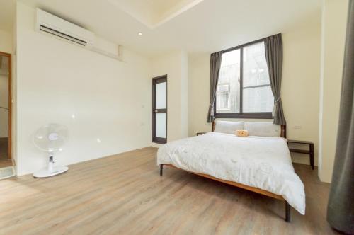 a white bedroom with a bed and a window at 聽故事台南民宿 有貓的民宿 in Tainan
