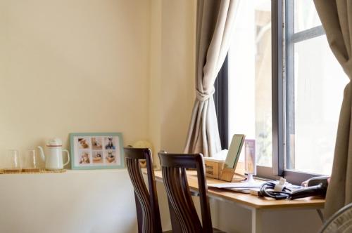 a desk with a laptop computer on it next to a window at 聽故事台南民宿 有貓的民宿 in Tainan