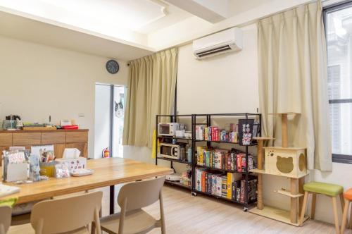 a room with a table and chairs and a book shelf at 聽故事台南民宿 有貓的民宿 in Tainan