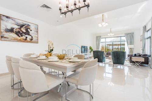 a white dining room with a table and chairs at Facing the Sea and Mountains 4BR Villa with Assistant Room and Private Pool, Al Dana Island, Fujairah by Deluxe Holiday Homes in Fujairah