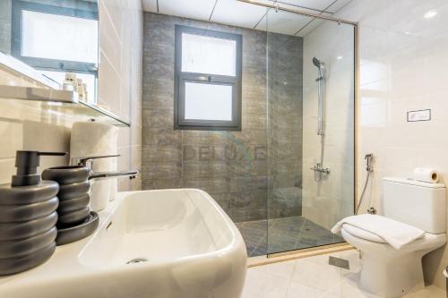 a bathroom with a shower and a sink and a toilet at Facing the Sea and Mountains 4BR Villa with Assistant Room and Private Pool, Al Dana Island, Fujairah by Deluxe Holiday Homes in Fujairah