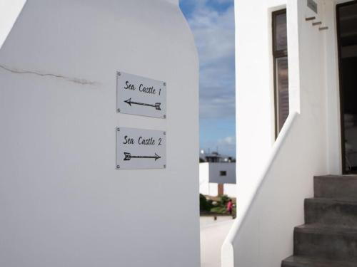 a sign on the side of a white house with stairs at Sea Castle's Paternoster in Paternoster
