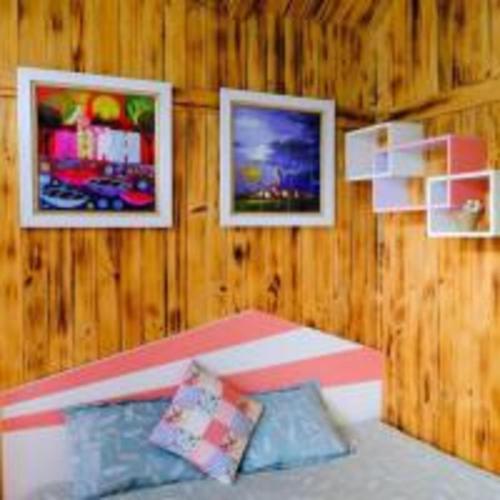 a bedroom with three pictures on a wooden wall at Roses Homestay- Venuestay in Tam Ðảo