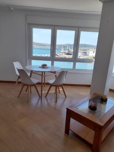 a living room with a table and chairs and windows at Mareira in Camariñas