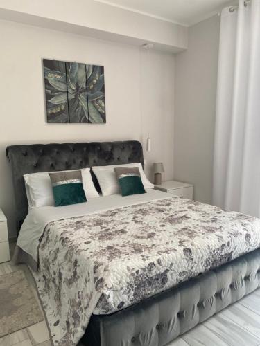 a white bedroom with a large bed with green pillows at Casa Letizia Pescara Centro in Pescara