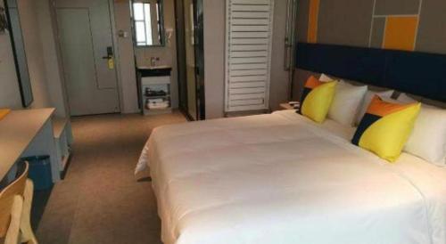 a bedroom with a large white bed with yellow pillows at 7 Days Inn Guangrao Bus Station in Dongying