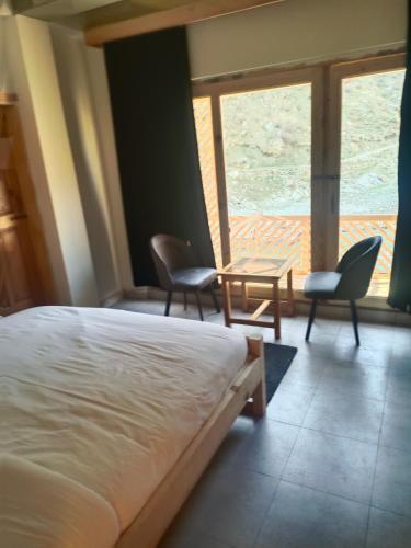a bedroom with a bed and two chairs and a table at Bela Resorts Naran in Nārān