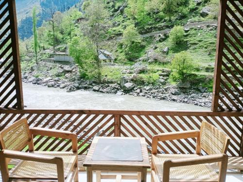 a porch with two chairs and a table and a river at Bela Resorts Naran in Nārān
