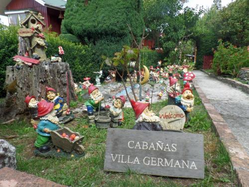 a group of figurines in a garden with a sign at Hostal y Cabañas Villa Germana in Puerto Varas