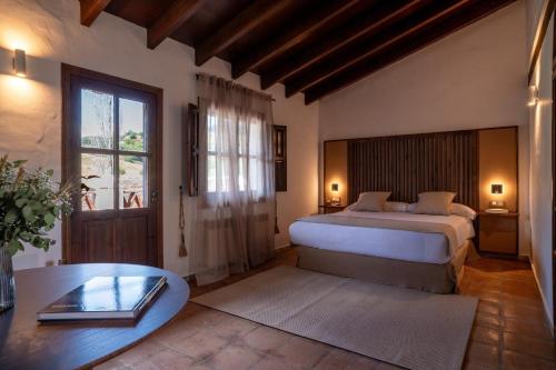 a bedroom with a bed and a table and a window at Málaga Sierra de las Nieves by Real Spain Hotels Adults Recommended in Casarabonela