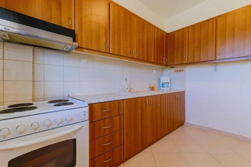 a kitchen with a white stove and wooden cabinets at Heliophilia 3-bdrm Maisonette in Nea Fokea in Nea Fokea