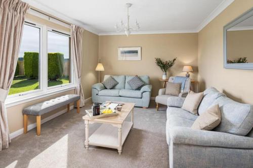 een woonkamer met twee banken en een tafel bij Muirton Cottage in Ardovie