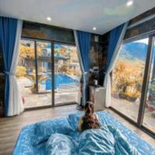 a dog sitting on a bed in a room with windows at Roses Homestay- Venuestay in Tam Ðảo