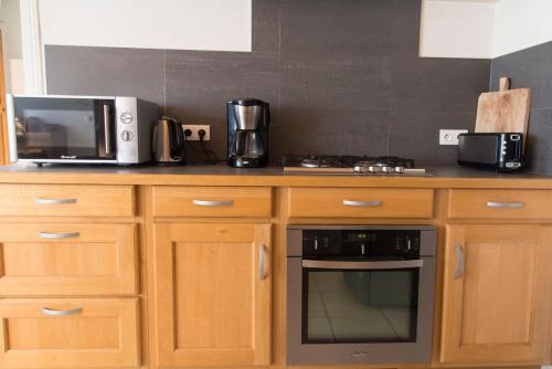 La cuisine est équipée de placards en bois, d'un four micro-ondes et d'une cuisinière. dans l'établissement La maison des Verdures, à Lus-la-Croix-Haute