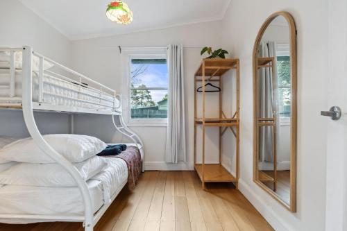 a bedroom with a bunk bed and a mirror at The Greenhouse - Cozy Blue Mountains Retreat in Blackheath