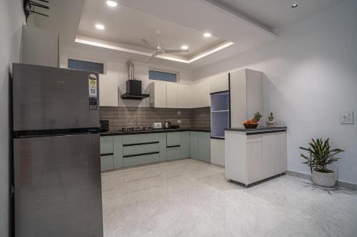 a large kitchen with white cabinets and a refrigerator at Alaya Stays Udgam Vilas Serene 5-BHK Apartment With Jacuzzi & Lift in Dehradun