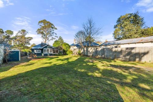 a yard with a fence and a house at The Greenhouse - Cozy Blue Mountains Retreat in Blackheath