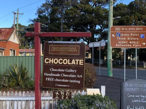 a sign in front of a street with signs at The Greenhouse - Cozy Blue Mountains Retreat in Blackheath