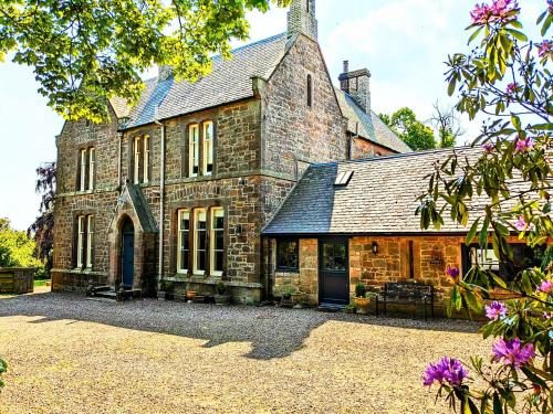 an old stone house with a driveway in front of it at Stable Lodge in Berwick-Upon-Tweed
