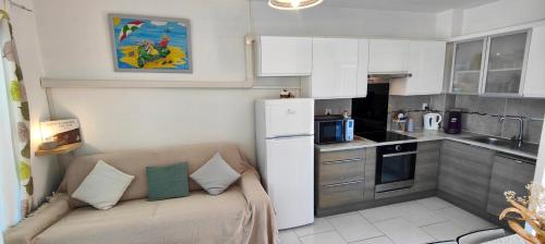 Elle comprend une petite cuisine avec un canapé et un réfrigérateur blanc. dans l'établissement Apartment with pool near the city center, à Fréjus