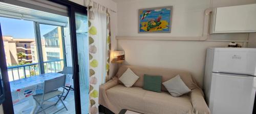 Elle comprend un petit salon avec un canapé et un balcon. dans l'établissement Apartment with pool near the city center, à Fréjus