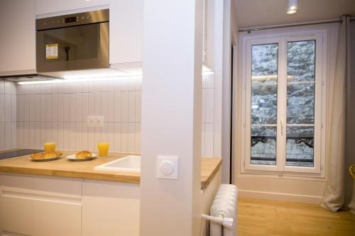 une cuisine blanche avec un évier et une fenêtre dans l'établissement Studio fonctionnel et moderne place Clichy - 2P, à Paris
