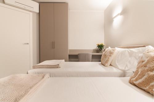 a white bedroom with two beds and a window at Villa Sabrina in Colico