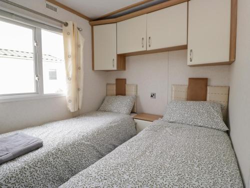two beds in a small room with white cabinets at Willow in Denny
