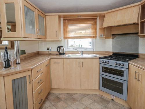 a kitchen with wooden cabinets and a sink at Birch in Denny