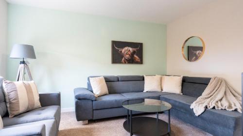 a living room with a blue couch and a table at Tummel Place in Grangemouth