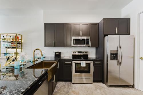a kitchen with black cabinets and stainless steel appliances at Modern 2BR, Family-Friendly in FLL, Near Beach! in Fort Lauderdale