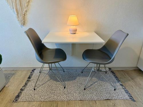Deux chaises et une table avec une lampe sur le dessus dans l'établissement Charmant studio I - accès privé, à Strasbourg