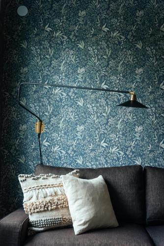 a lamp and a couch in a room with blue wallpaper at Gårdshuset Vandrarhem in Undersåker