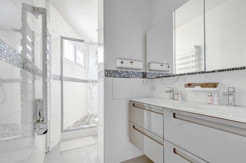 une salle de bain blanche avec un lavabo et une douche dans l'établissement Suite Charlie Cardinet - Opulence au cœur de Paris, à Paris