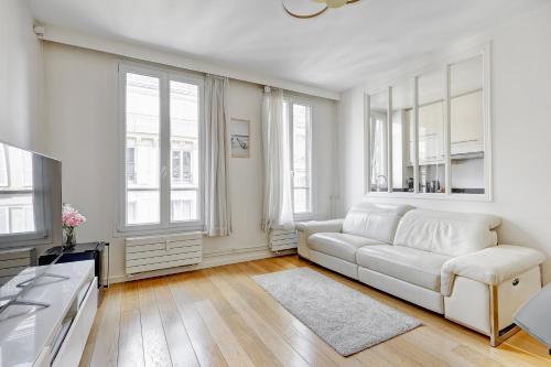 - un salon blanc avec un canapé blanc et des fenêtres dans l'établissement Suite Charlie Cardinet - Opulence au cœur de Paris, à Paris