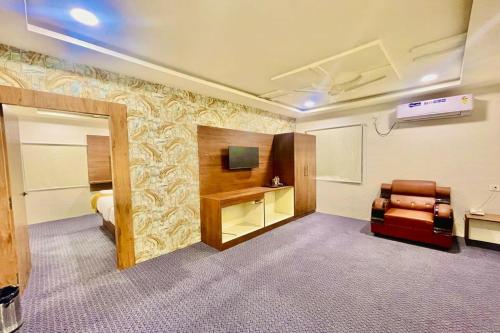a room with a bed and a chair and a television at Hotel Eagle Grand Airport Zone in Shamshabad