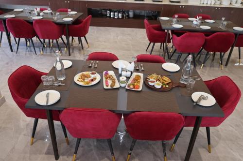 a dining room with tables and red chairs with food on them at Pallacia A Luxury Hotel in Beāwar